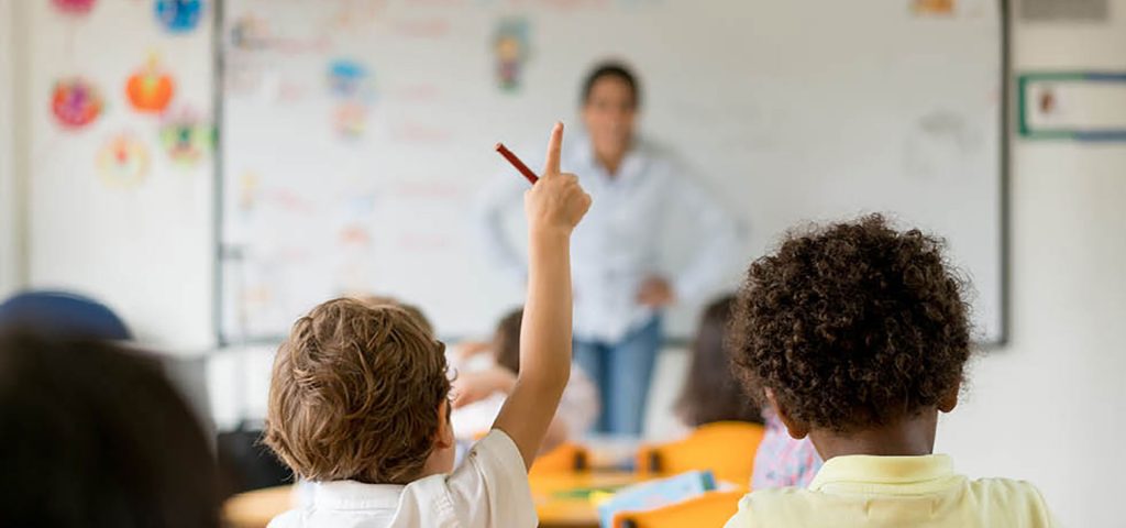 child with hand raised in classroom