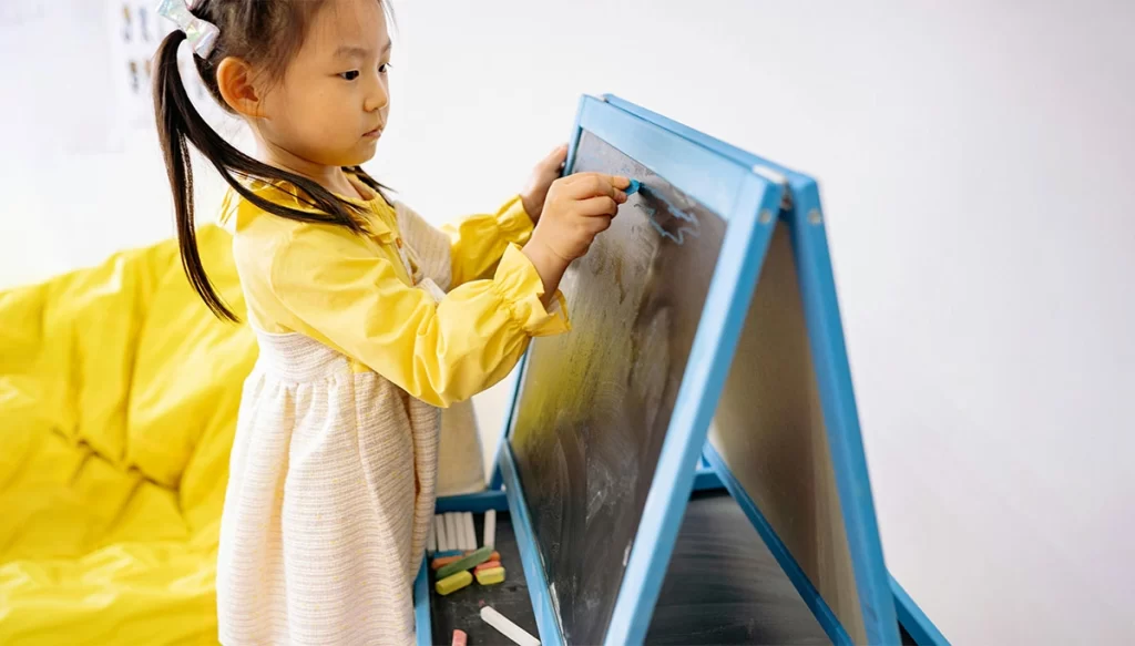 little girl writing on a blackboard