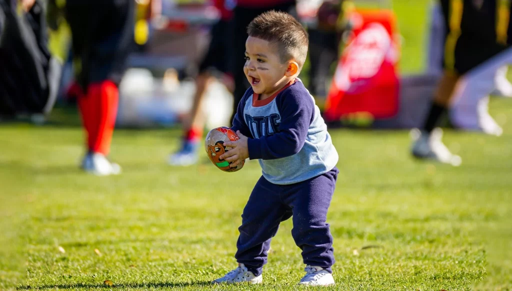 toddler with a football on a field
