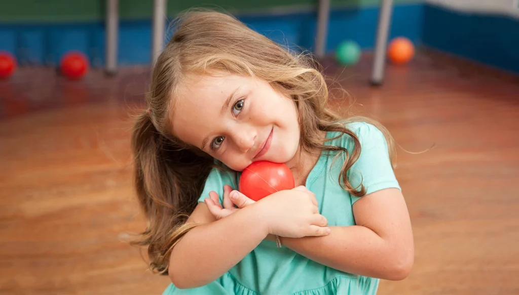 child holding ball and smiling