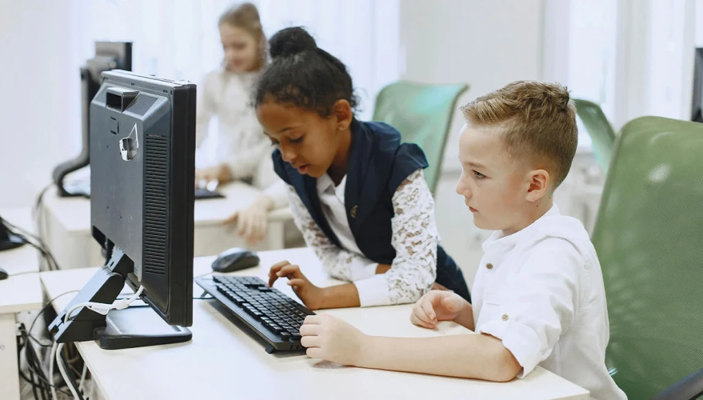 children typing and looking at a computer screen,