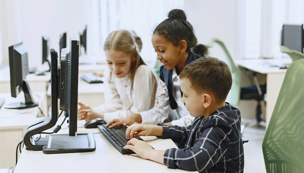 children typing on a keyboard in a computer room