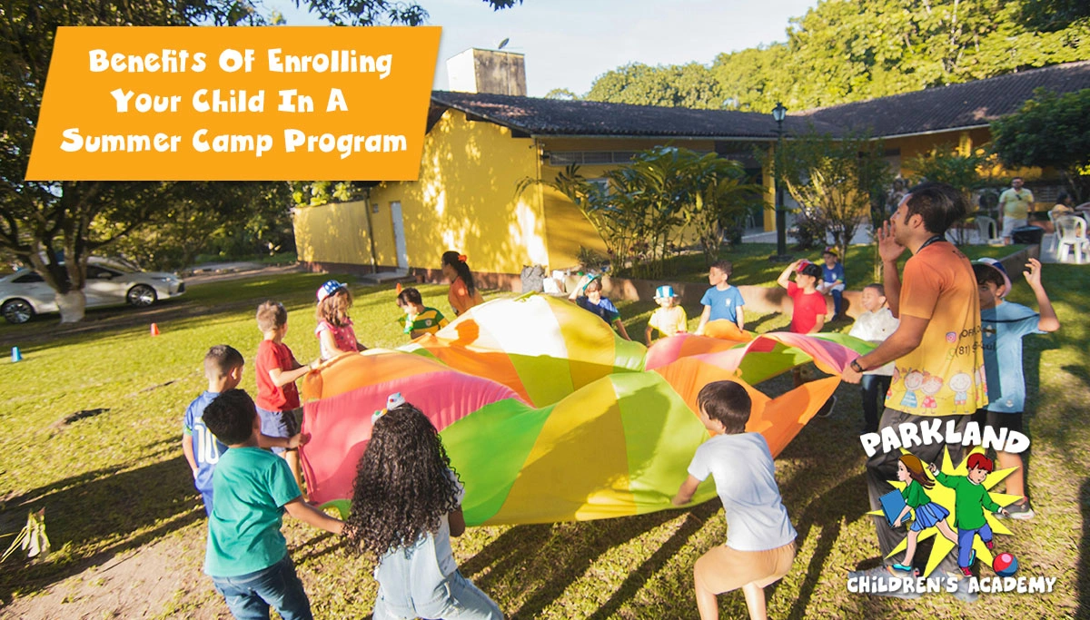 Group of children playing with a colorful parachute outside during a sunny day party.